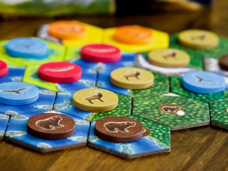 Tiles placement game with beautiful components - wooden tokens with bear, elk, salmon, fox and hawks. Cascadia Board Game by AEG and Flatout 