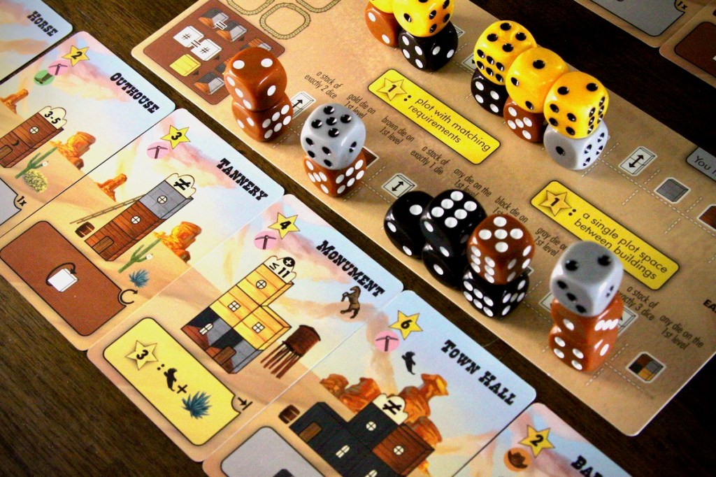 Example of a player mat full of dice buildings and building cards in Tumble Town board game by Weird Giraffe Games